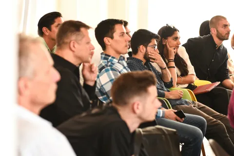 Attendees look on pensively during a presentation at a conference